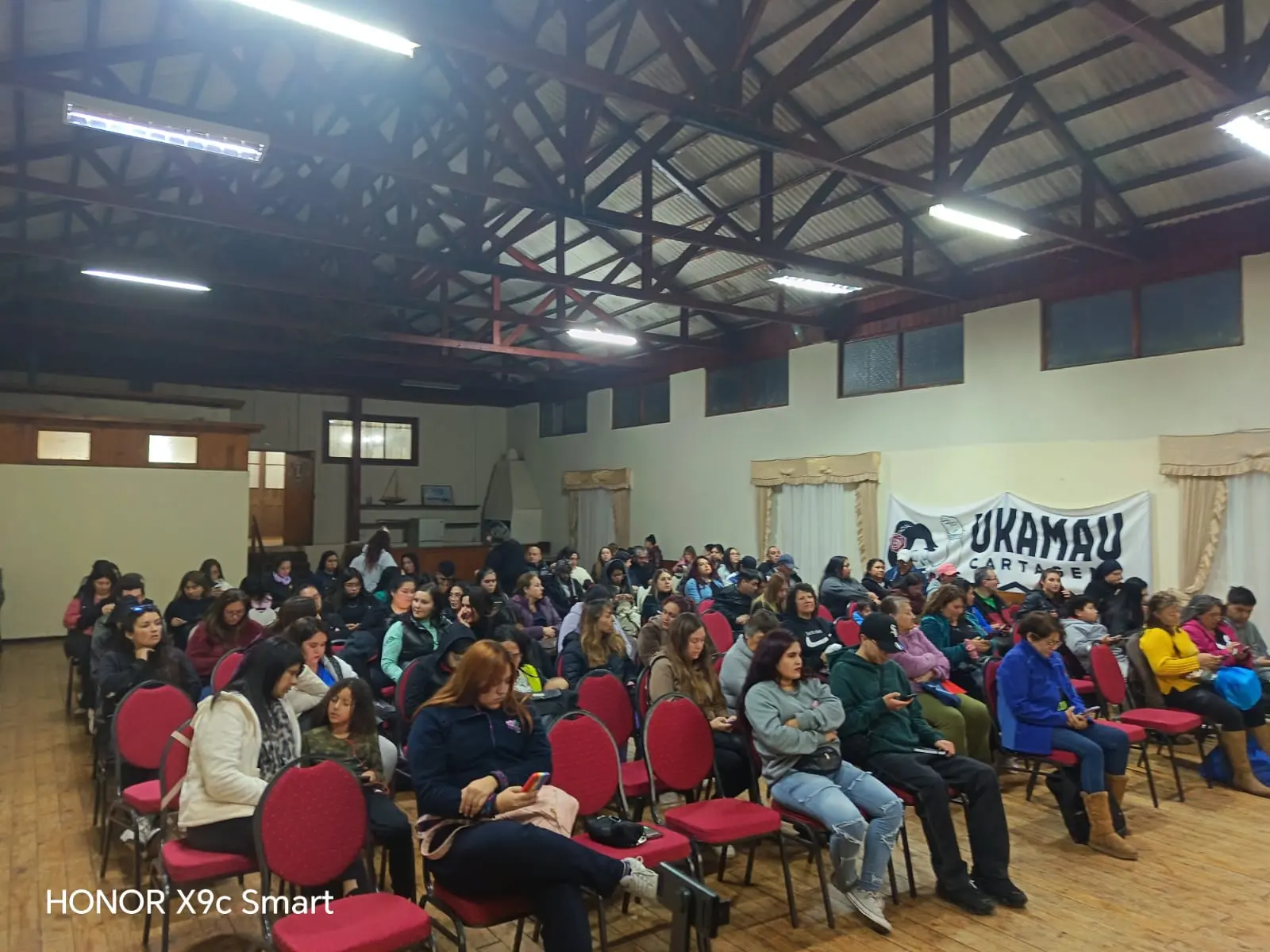 Salón lleno de socias y socios con banner Ukamau Cartagena